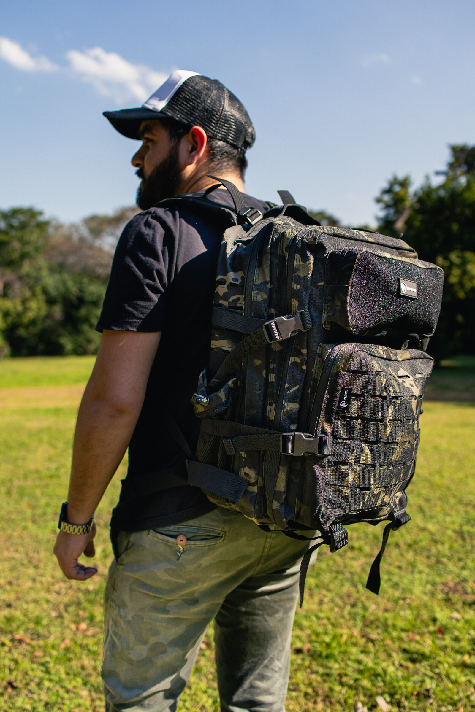 Hombre con mochila táctica camuflada en el campo